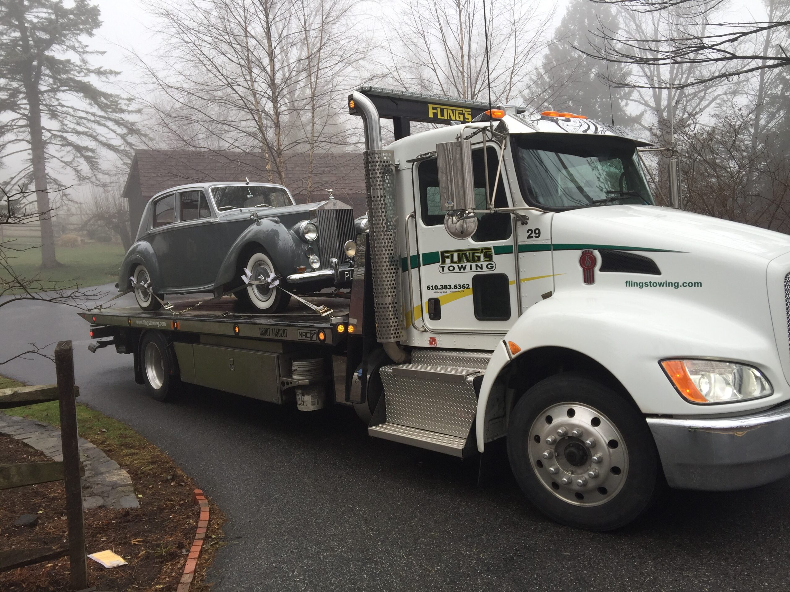 Classic car being strapped and towed on a flatbed tow truck on Thorndale PA